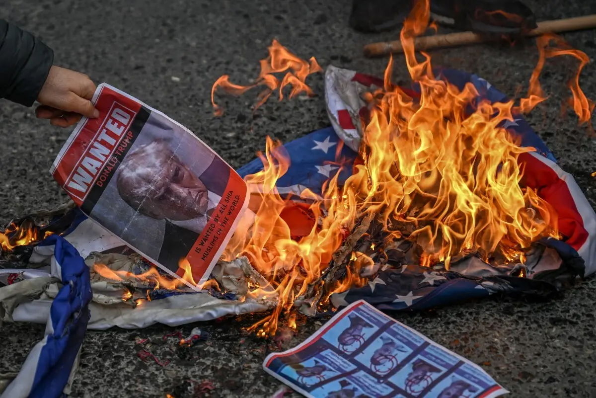 A protestor sets fire to an image depicting the mugshot of US President Donald Trump and reading "Wanted Donald Trump is wanted by all Shia Muslims in the world" as they gather to protest against the US and Israel attack of Iran and the killing of the Supreme leader in front of Israel Consulate in Istanbul on March 1, 2026. The United States and Israel launched strikes against Iran on February 28, 2026 sparking fears of regional war with explosions reported across the Middle East as the Islamic republic retaliated with barrages of missiles. (Photo by Ozan KOSE / AFP)