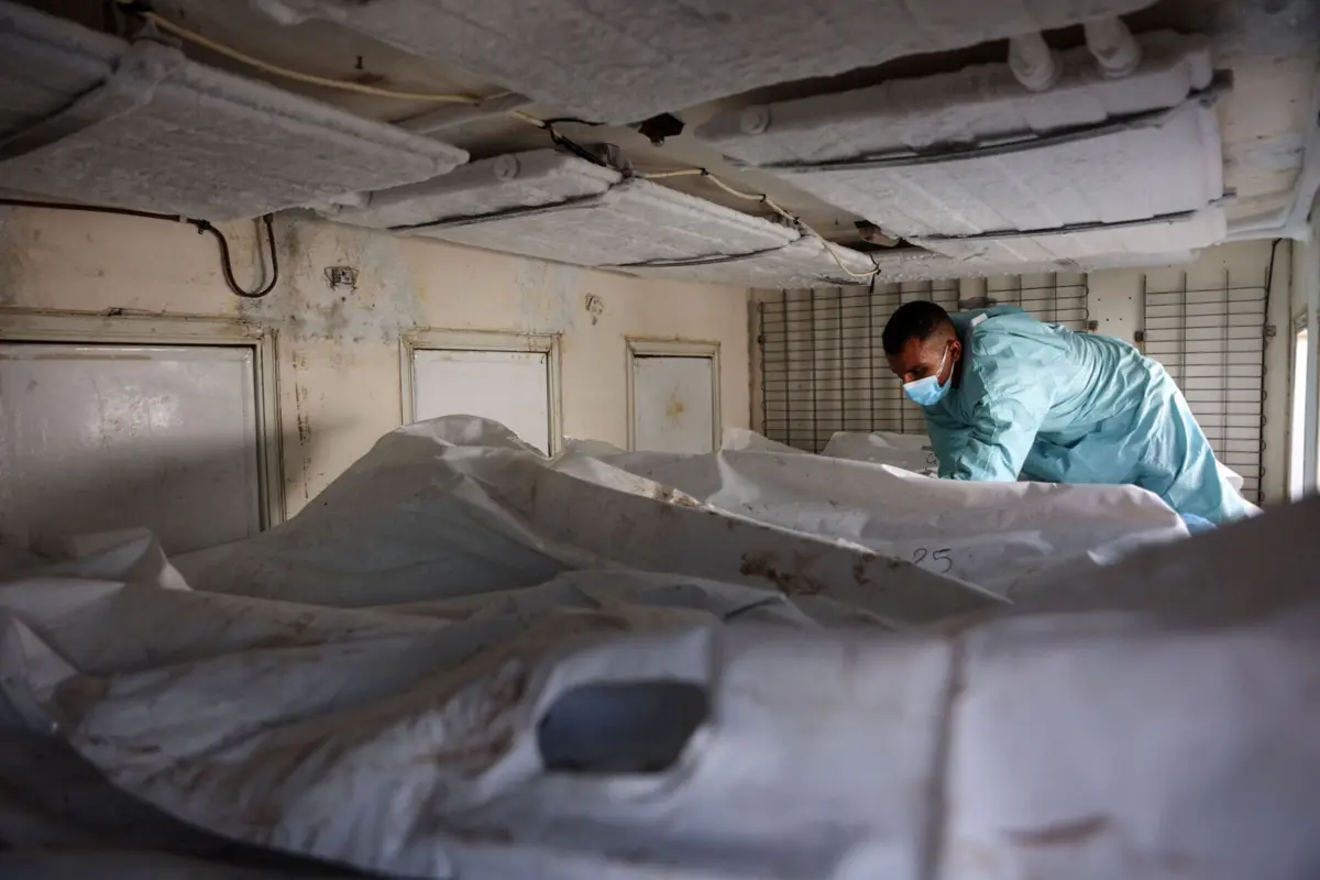 Um profissional de saúde verifica os corpos devolvidos por Israel numa carrinha refrigerada