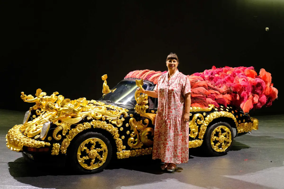 Joana Vasconcelos junto ao seu Porsche-coche, com talha dourada e plumas.