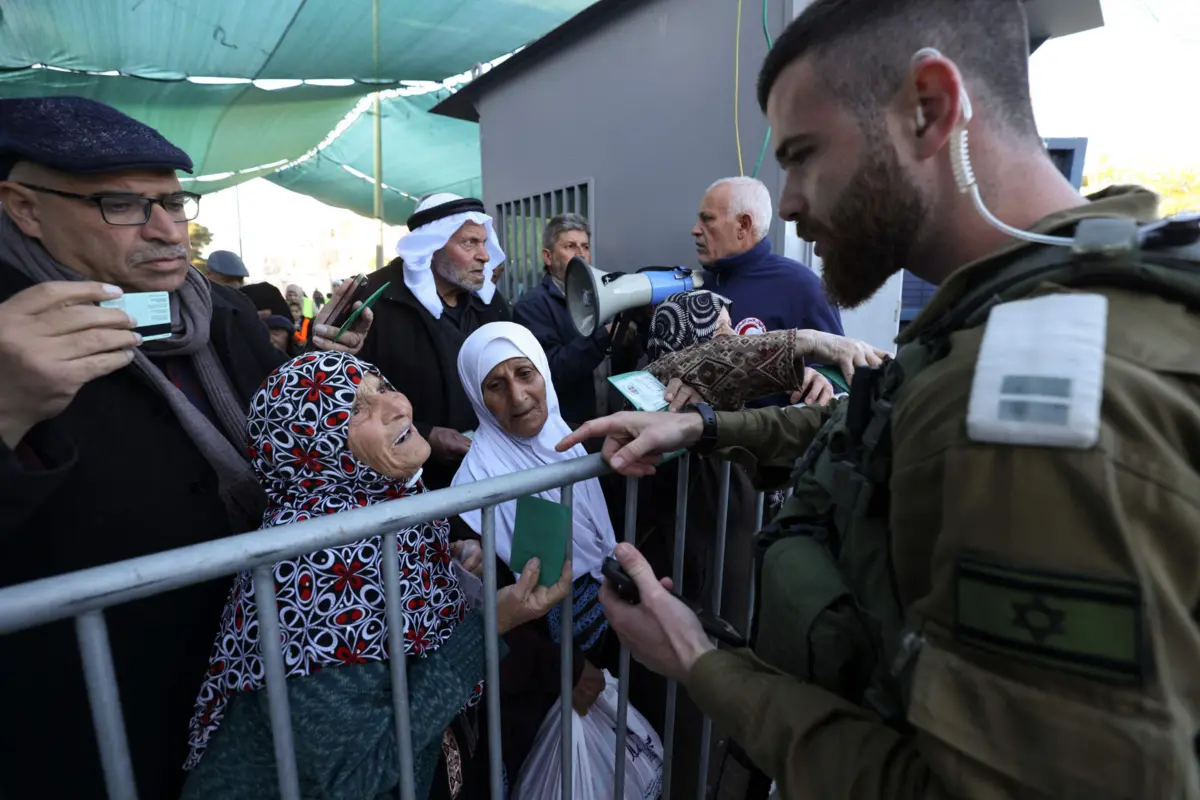 Militar israelita verifica os bilhetes de identidade e as autorizações de palestinianos que tentam passar por um posto de controlo em Belém, na Cisjordânia ocupada, para chegar a Jerusalém (15 de março)