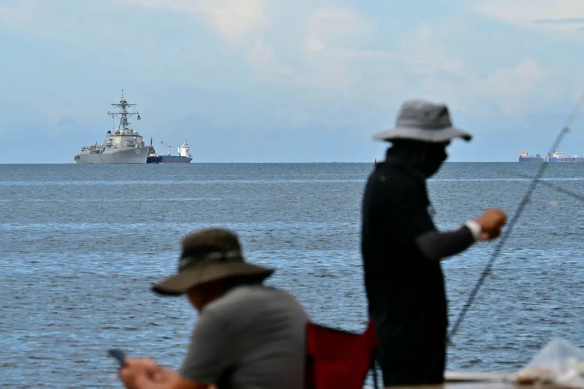 Navio de guerra USS Gravely é visto à distância na costa de Port of Spain, a 26 de outubro de 2025, enquanto pescadores pescam na capital de Trinidad