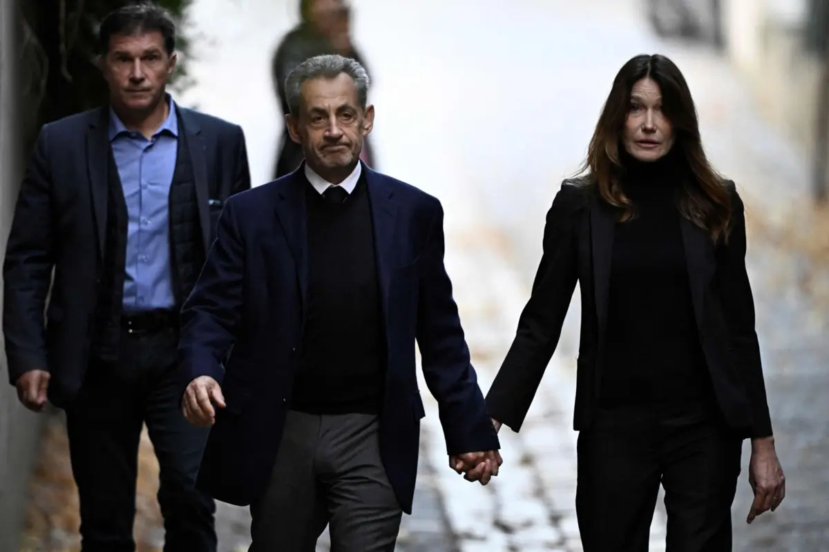 Sarkozy no dia em que foi detido, à saída da sua residência, de mão dada com a mulher, Carla Bruni