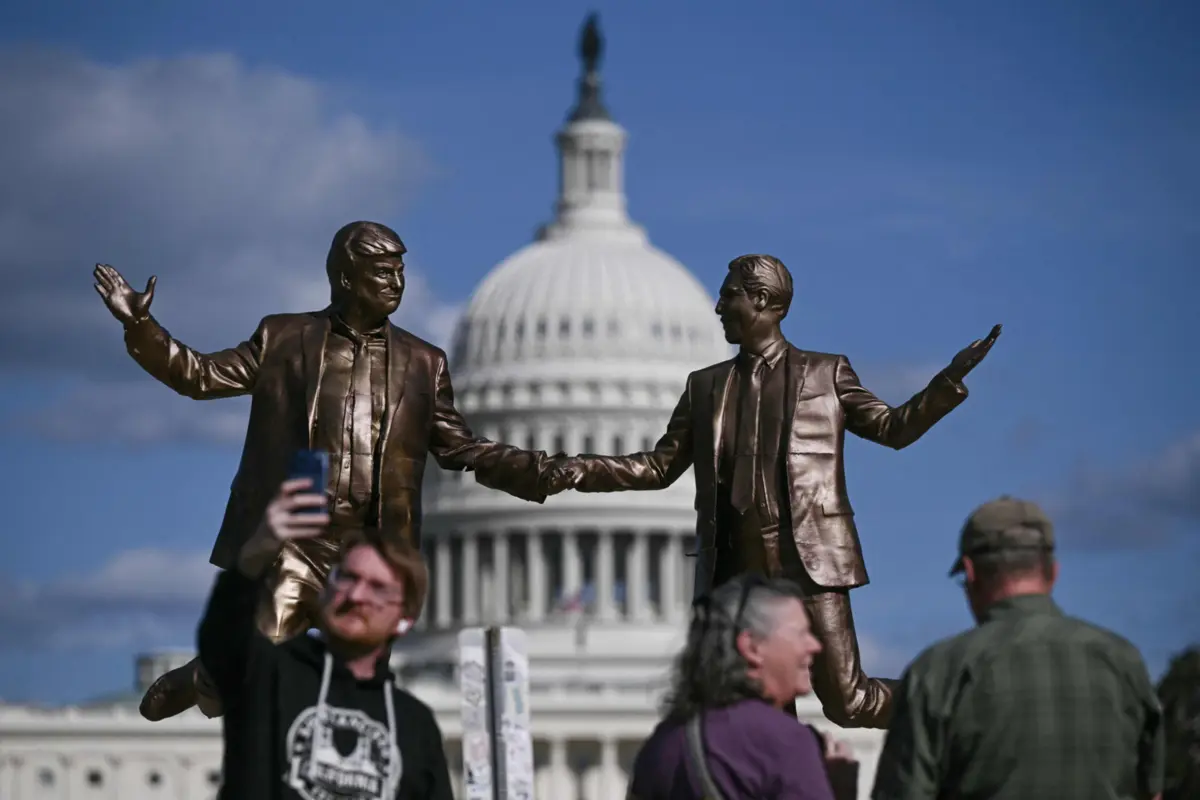 Pessoas posam para as fotografias junto a uma estátua que retrata o presidente dos EUA, Donald Trump, e Jeffrey Epstein de mãos dadas.
