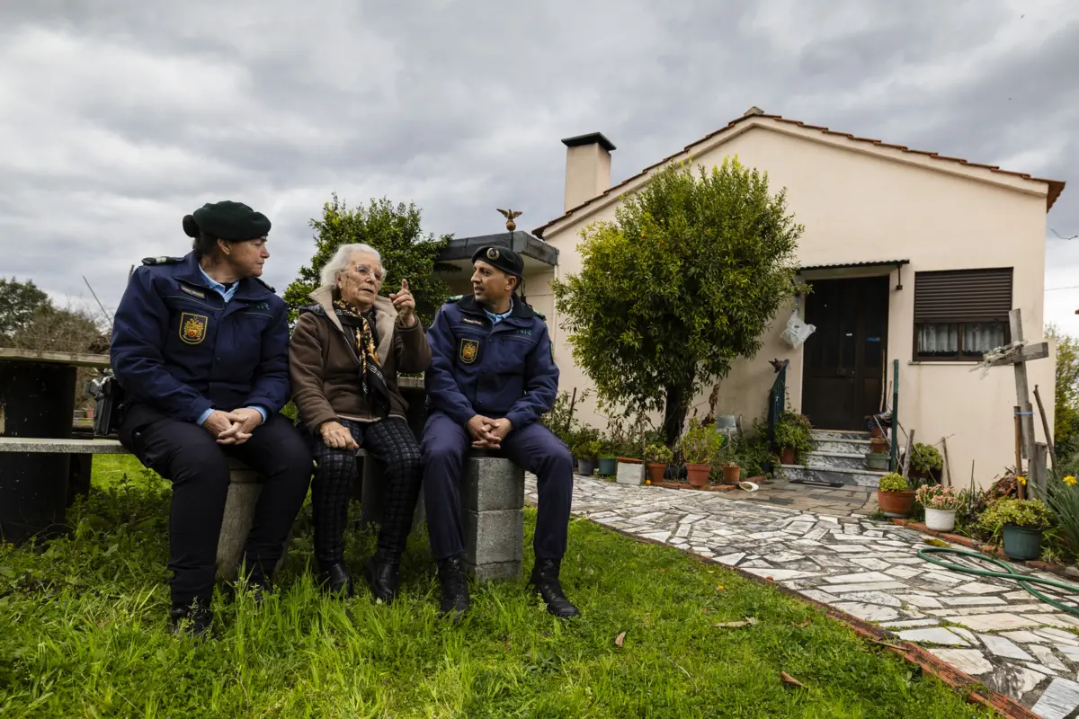 Anunciação Simões sentada à porta de casa, no concelho de Tondela, com os “amigos” da GNR
