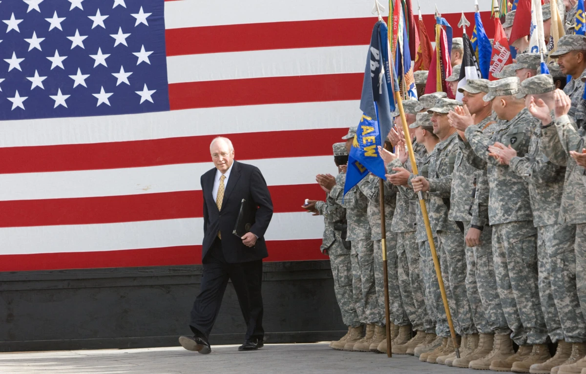 Dick Cheney sobe ao palco a 18 de Março de 2008 para discursar às tropas norte-americanas estacionadas na Base Aérea de Balad, no Iraque.
