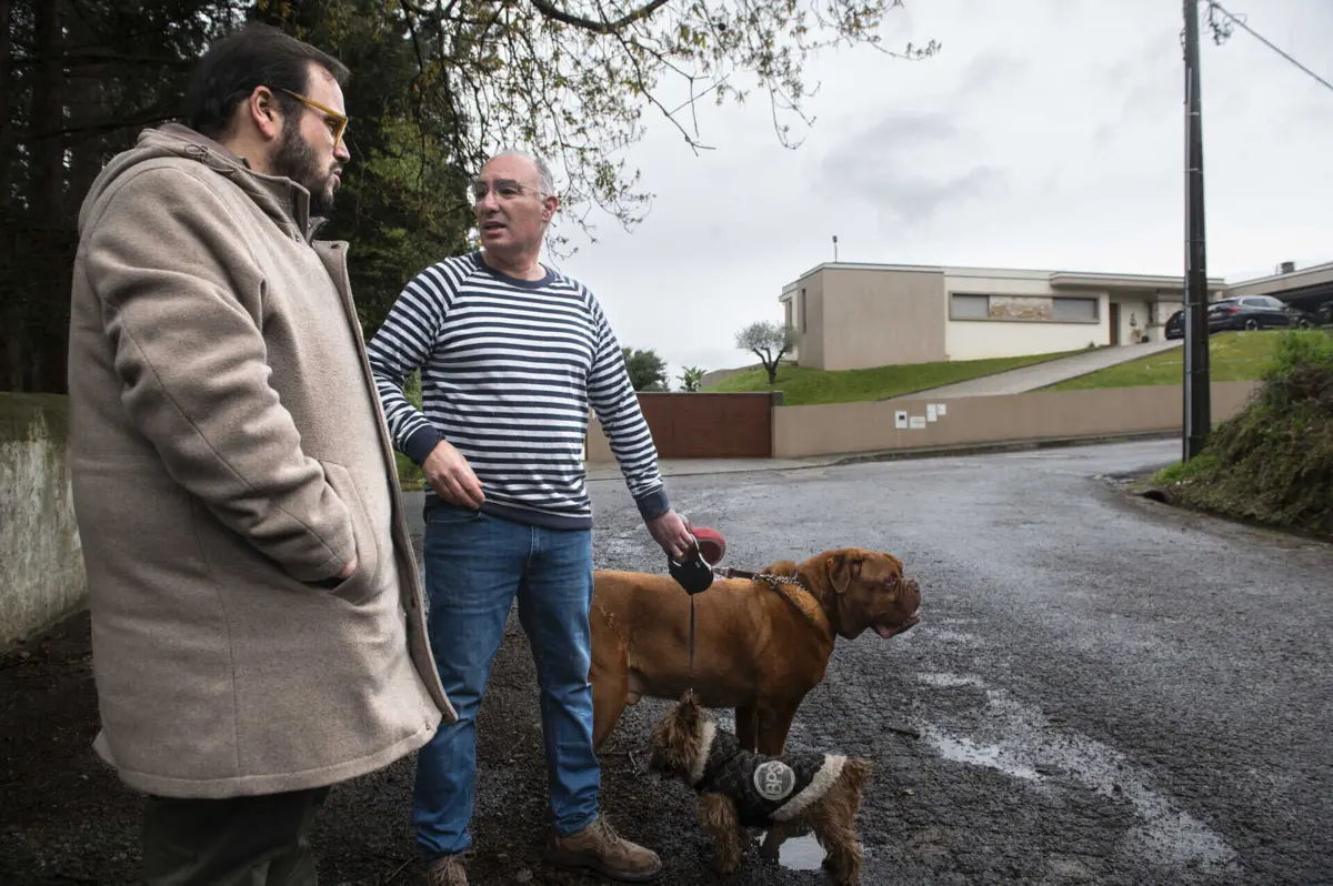 Nuno Almeida, da União de Freguesias, e Pedro Adrego (com os cães), residente em risco de perder a vivenda que se vê ao fundo
