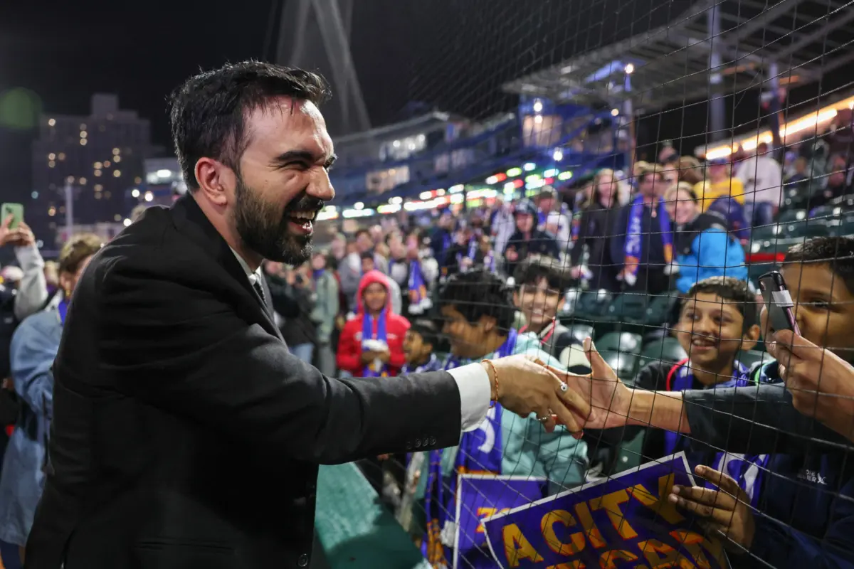 Mamdani cumprimenta jovens em jogo de futebol