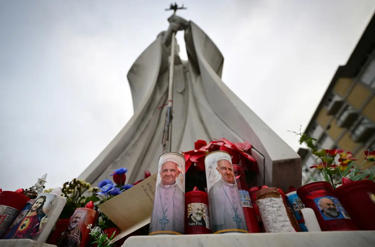 Velas pelas melhoras de Francisco junto à estátua de João Paulo II em frente ao hospital onde o Papa está internado