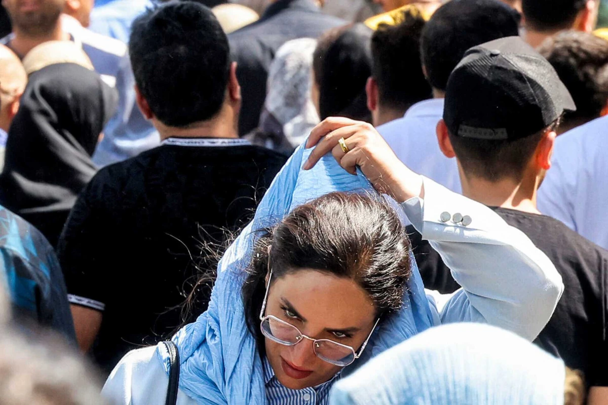 Mulher ajeita o hijab num mercado em Teerão