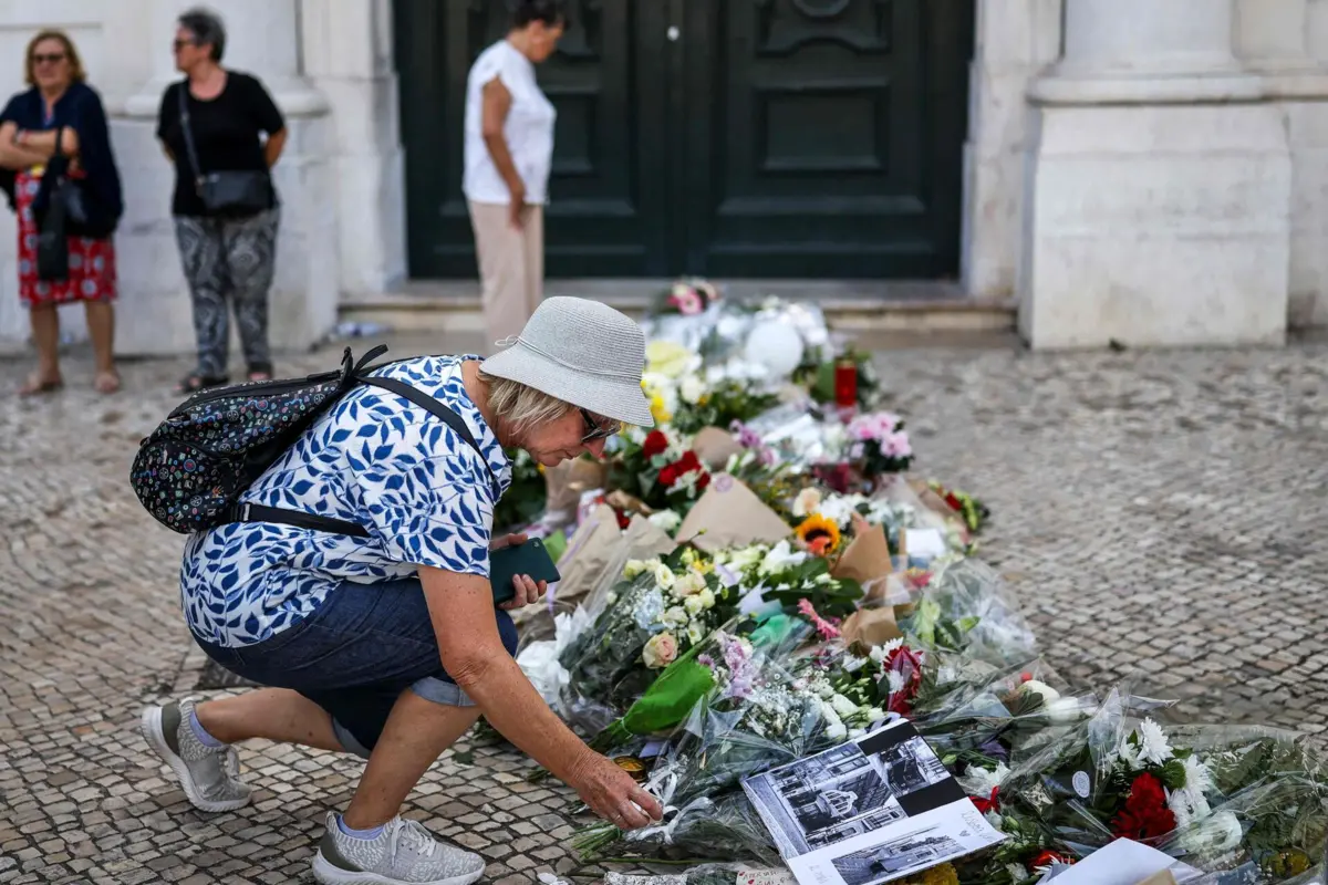 Mulher deposita flores junto ao local onde o acidente matou 16 pessoas, na quarta-feira ao final da tarde