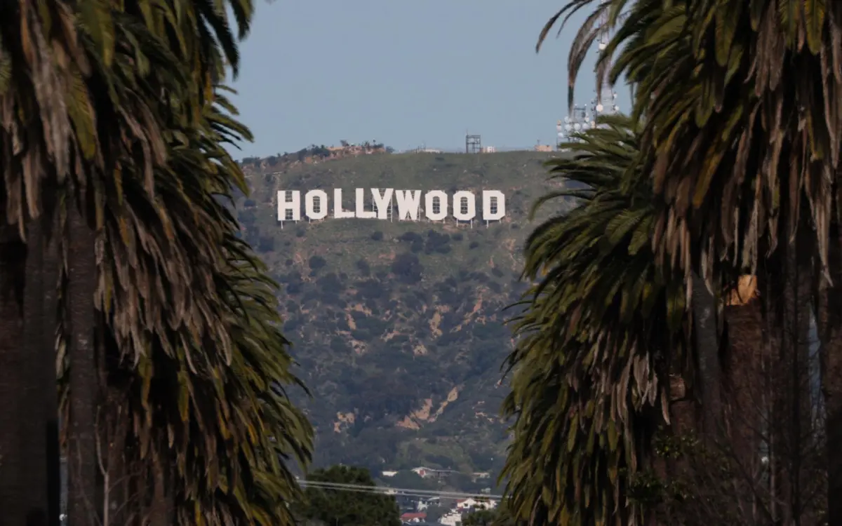 The Hollywood sign is framed by palm trees standing along a residential street in Los Angeles, California on January 28, 2026. (Photo by Patrick T. Fallon / AFP)