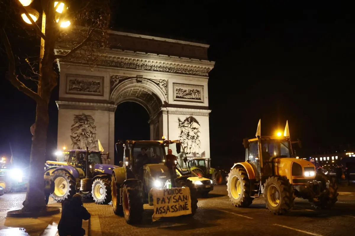Agricultores franceses junto ao Arco do Triunfo conduzem tratores em direção à Champs-Élysées.