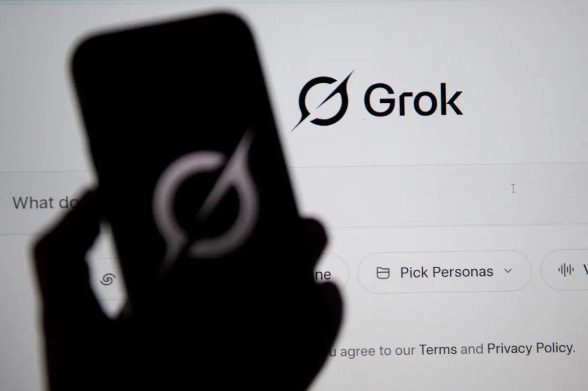 In this photo illustration, the Grok website is seen on a computer screen next to a mobile phone displaying the logo in Bogota on February 12, 2026. Brazilian authorities reported on February 12 that they had ordered billionaire Elon Musk's social network X to take immediate action to prevent the creation of sexual images generated by Grok, its artificial intelligence (AI) assistant. (Photo by Pablo VERA / AFP)