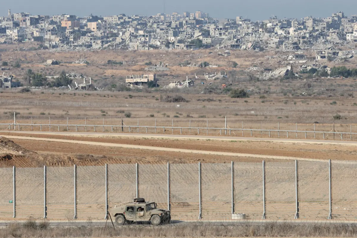 Veículo militar israelita patrulha fronteira no Sul de Israel. Ao fundo, está o campo de refugiados de Bureij, na região central de Gaza, arrasada pelos ataques hebraicos durante dois anos.