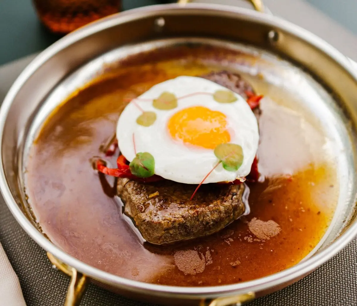 O bife do lombo, frito, vem com pimenta da terra, ovo estrelado, molho e batatas fritas.