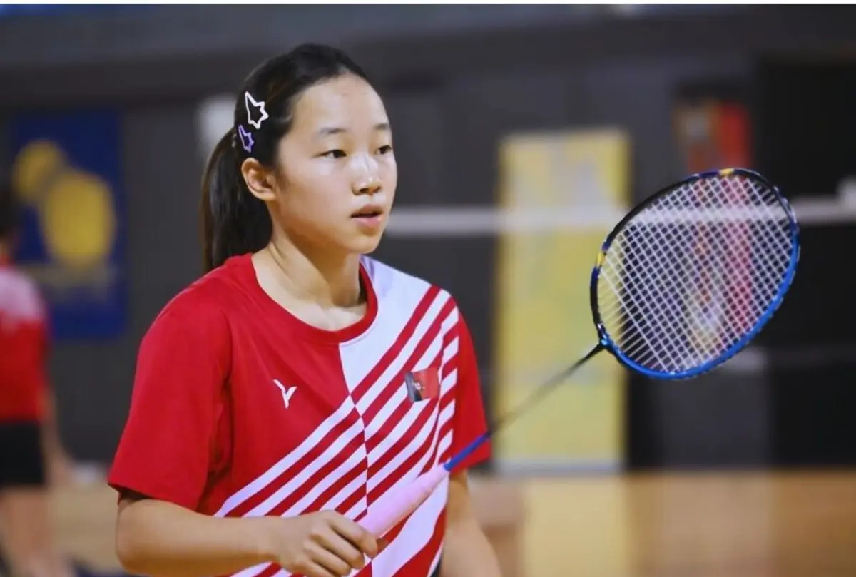 Hok In Lam perto do quadro principal dos internacionais de Bona em badminton