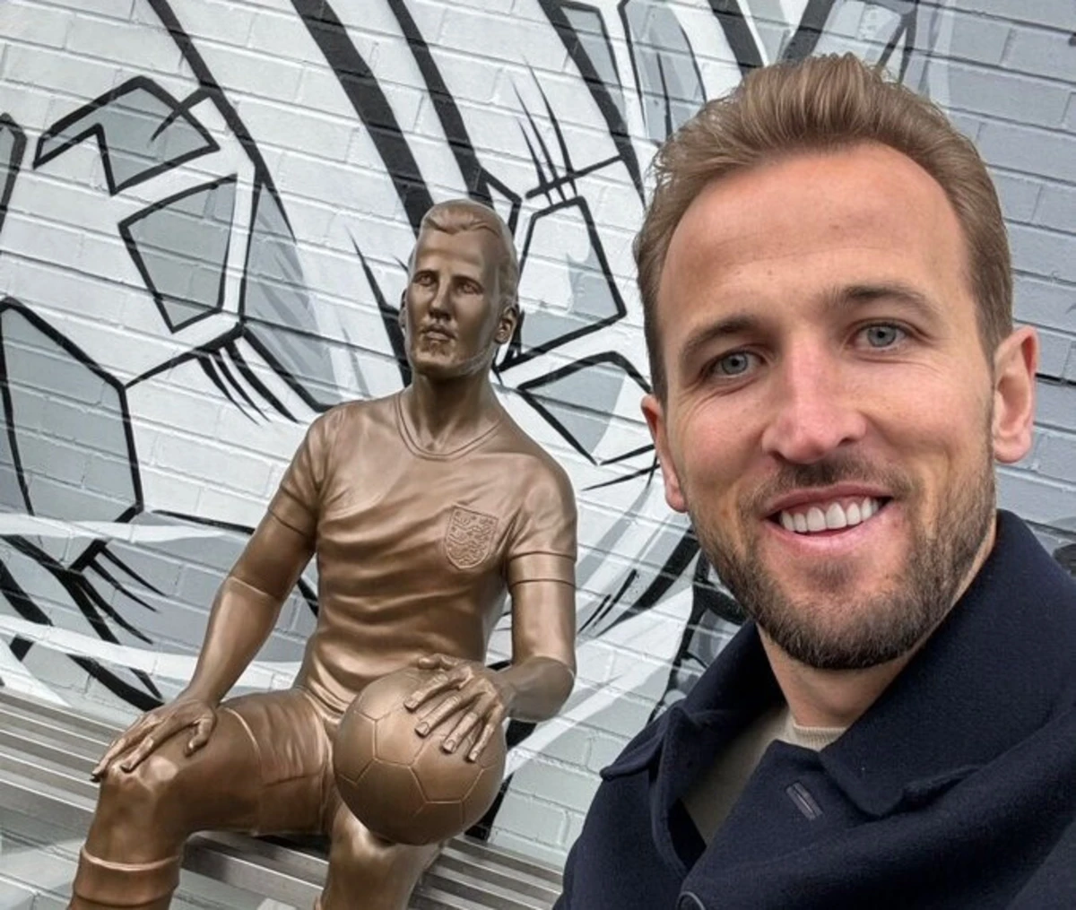 Kane posa ao lado da sua estátua (créditos: X/Reprodução)