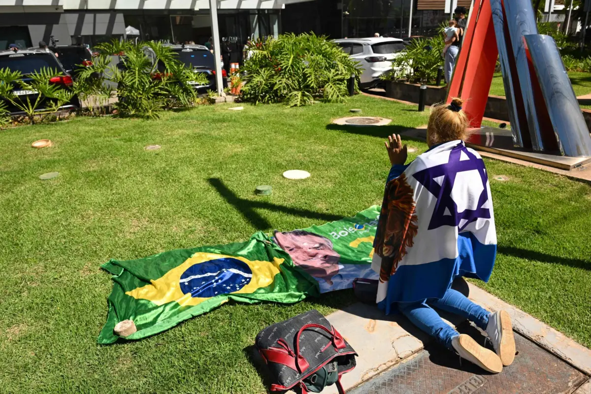 Uma mulher em oração por Jair Bolsonaro nas imediações do Hospital DF Star