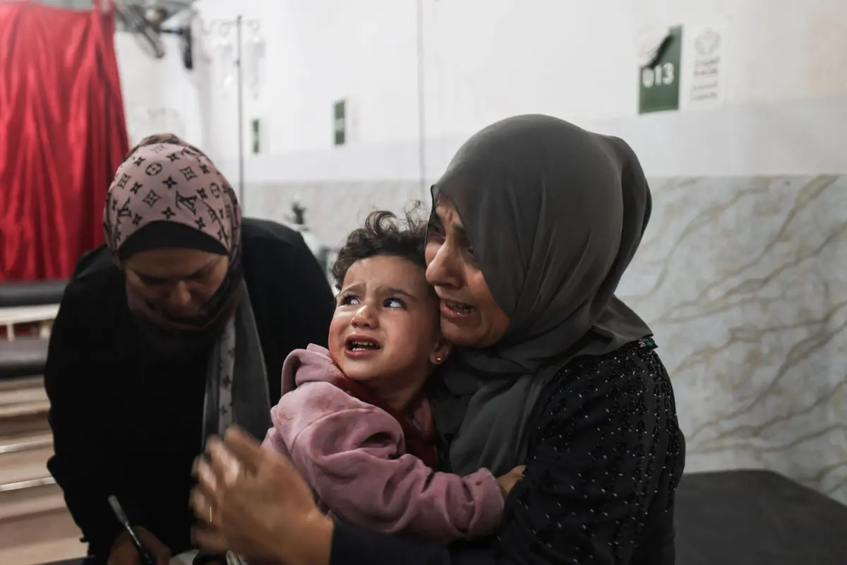 EDITORS NOTE: Graphic content / An injured Palestinian child reacts at Al-Awda Hospital at the Nuseirat refugee camp in the central Gaza Strip, as casualties are brought into the medical facility following Israeli strikes on November 22, 2025. Israel and Hamas agreed to a US-brokered ceasefire that came into effect on October 10 after more than two years of war, but strikes have continued to take place, with both sides accusing the other of violating the truce. (Photo by Eyad Baba / AFP)