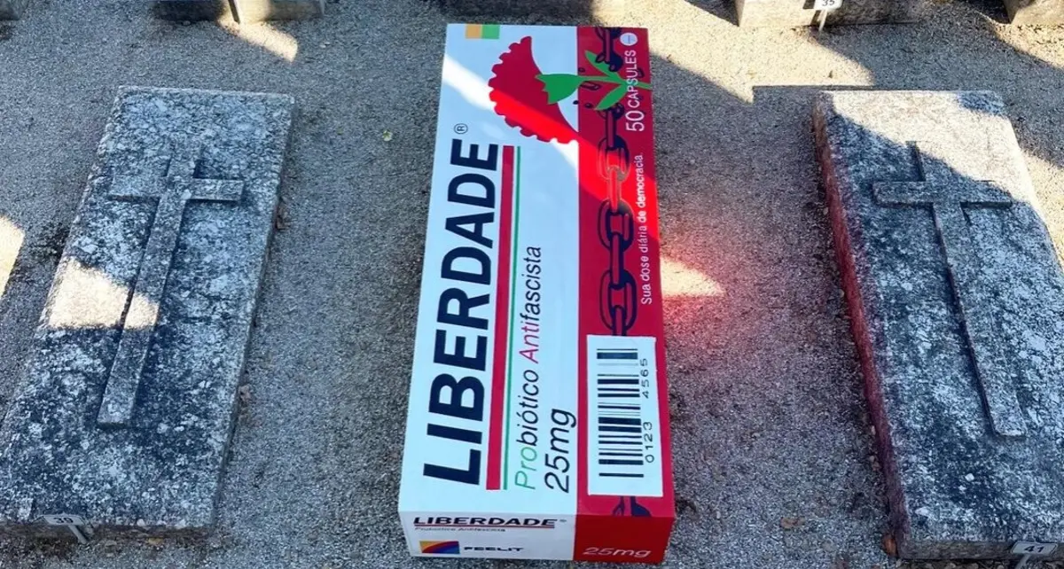 Imagem de contexto do artigo "Liberdade: probiótico antifascista." Bordallo II coloca caixa de medicamentos a tapar campa de Salazar